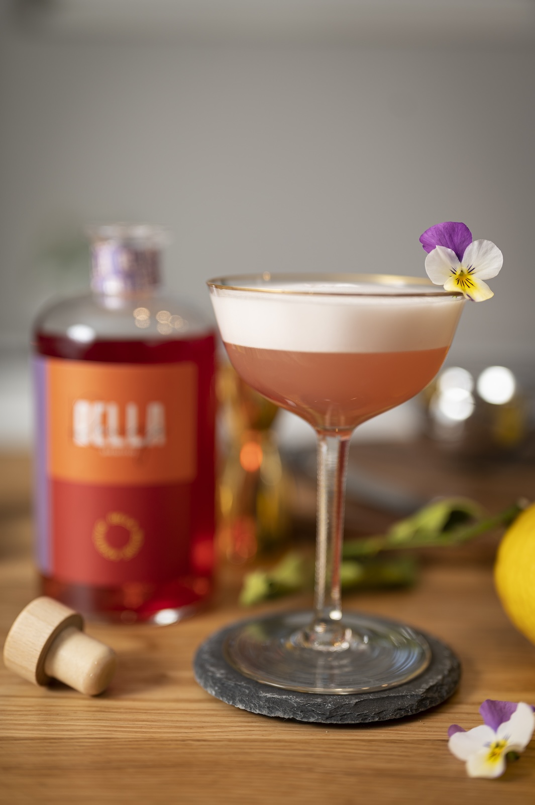 Cocktail im Stielglas neben einer Flasche Bella Rouge von Heimat Heroes