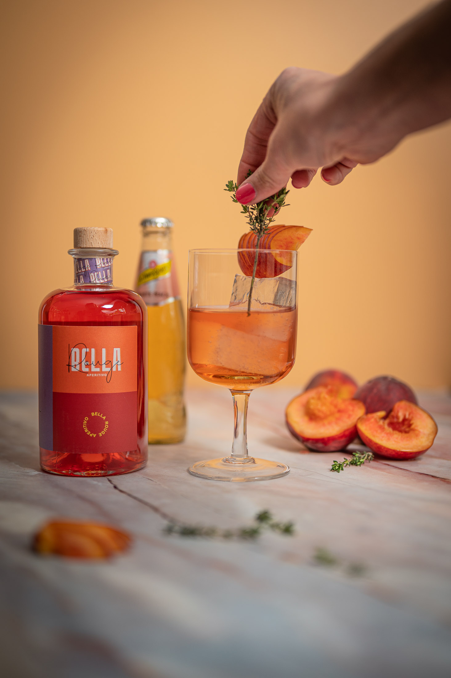 Ein Drink mit Pfirsich wird neben der Bella-Rouge-Flasche mit Minze garniert