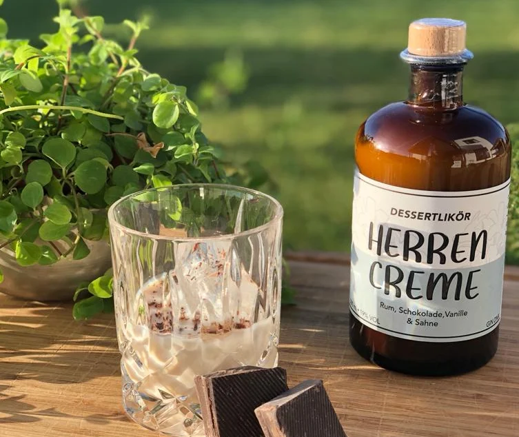 Herrencreme Likör von Heimat Heroes neben einem Glas mit Eis und Schokolade